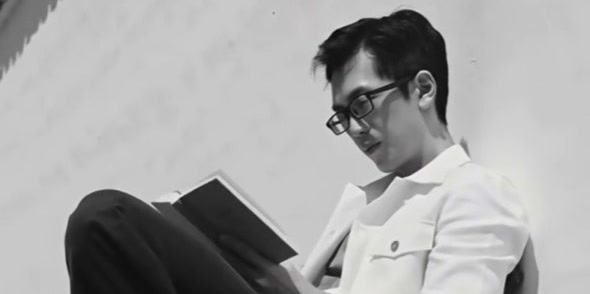 Chia Hao Kuo seated outdoors while reading a book.